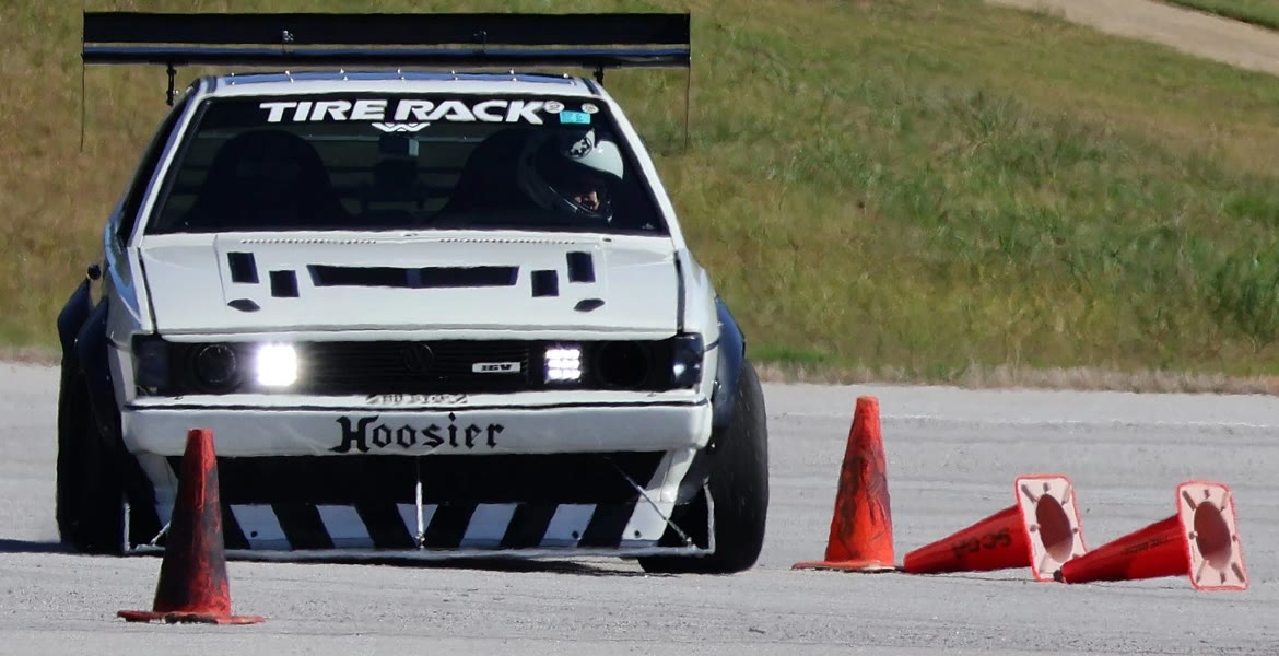 A prepared Volkswagen at speed on an autocross course, cones knocked flat beside it.